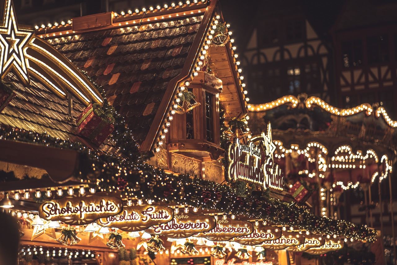 Christmas Market in Europe showing a vendor booth lit with Christmas lights and decorated with garla